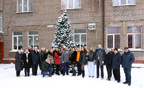 Колектив коледжу біля новорічної ялинки на подвір’ї після підсумкових заходів 2025 року